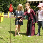 drei Mädchen beim spielen mit Hufeisen, auf einer schönen grünen Wiese, auf einem mittelalterlichen Fest im Sommer